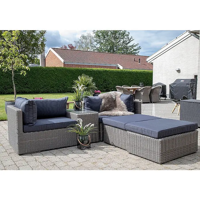 Ebuy24 Loungemöbel-Set Rosino - 3 -tlg., Polyrattan, Aluminium, Glas, Polyester, Grau - Grau-meliertes Polyrattan-Lounge-Set mit dunklen Kissen auf einer gepflasterten Terrasse.