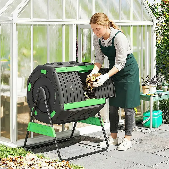 Outsunny Komposter - 200 l - Eine Frau füllt Blätter in einen schwarz-grünen rotierenden Komposter im Garten.