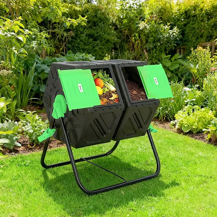 Outsunny Komposter - 130 l, 67 x 60 x 77 cm - Schwarzer Doppelkammer-Trommelkomposter mit grünen Deckeln, eine Kammer mit Bioabfällen gefüllt, in einem sonnigen Garten.