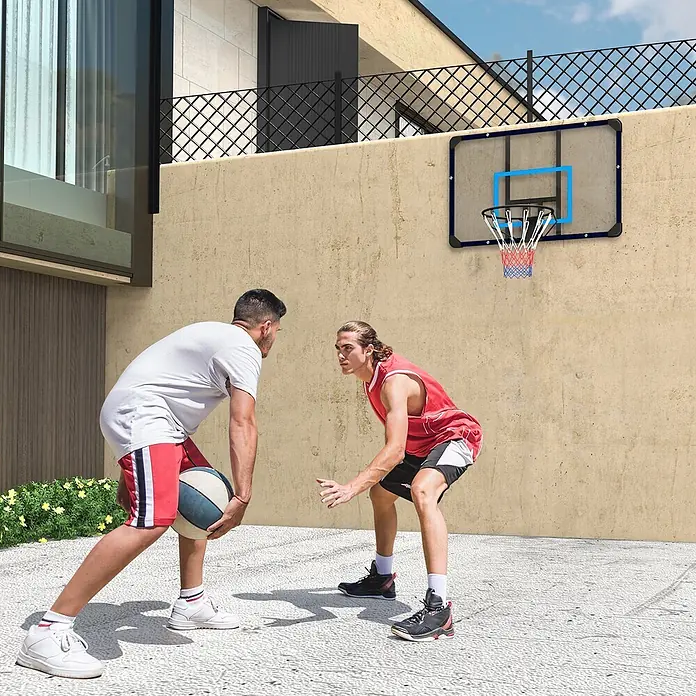 Sportnow Basketballkorb - Stahl, Schwarz, Transparent, Blau - Zwei Männer spielen Basketball mit einem wandmontierten Korb mit transparenter Platte und blauem Rand.