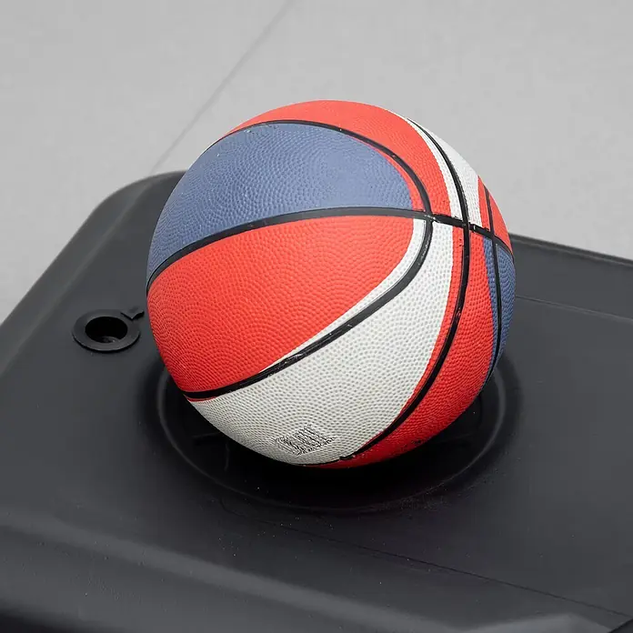 Homcom Basketballkorb - Stahl, Schwarz - Ein bunter Mini-Basketball mit roten, blauen und weißen Paneelen ruht auf einem schwarzen Plastiksockel.