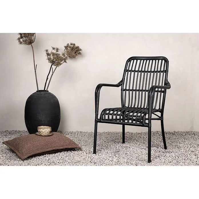 Ebuy24 Gartensessel Rizal - 1 Stk., Aluminum, Rattan, Korbmöbel, Schwarz, B x T x H: 57 x 64 x 90 cm - Schwarzer Rattan-Sessel auf Kiesboden neben einer Vase mit Trockenblumen.
