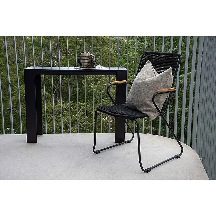 Ebuy24 Gartensessel Bois - 1 Stk., Teak, Natur, B x T x H: 55 x 51 x 82 cm - Schwarzer Outdoor-Konsolentisch und passender Stuhl mit Seilgeflecht, Holzarmlehnen und hellem Kissen auf einem Balkon.