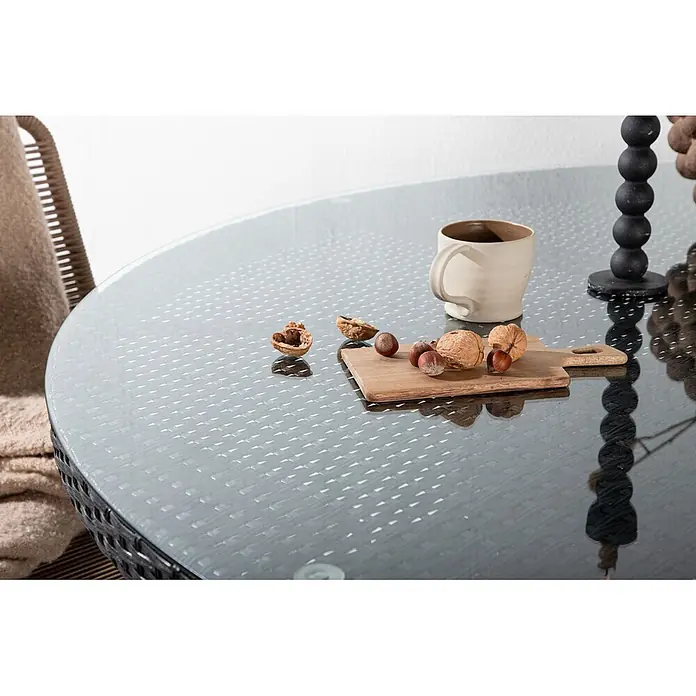 Ebuy24 Gartentisch rund Volta - Ø x H: 150 x 74 cm, Aluminium, Glas, Rattan, Schwarz, Stapelbar - Runder Glastisch mit subtilem Flechtmuster für den Außenbereich, dekoriert mit Tasse und Nüssen.