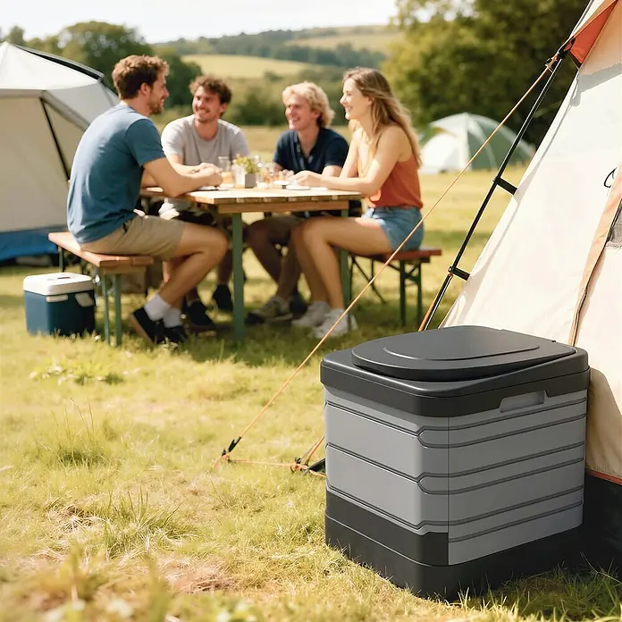 Outsunny Campingtoilette - Kunststoff - Grau-schwarze tragbare Campingtoilette neben einem Zelt auf einem Campingplatz.