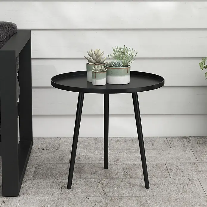 Outsunny Garten-Beistelltisch rund - Ø x H: 40 x 50 cm, Stahl, Schwarz - Schwarzer runder Metall-Beistelltisch mit drei Beinen, der Topfpflanzen neben einem Outdoor-Sofa hält.