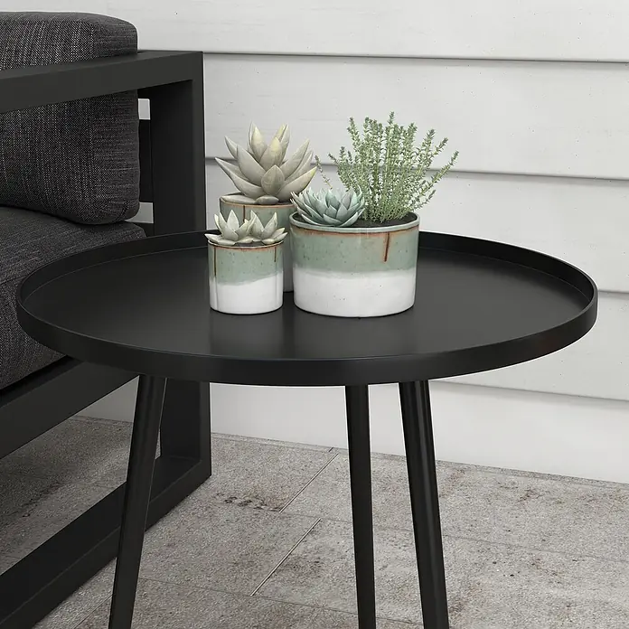 Outsunny Garten-Beistelltisch rund - Ø x H: 40 x 50 cm, Stahl, Schwarz - Schwarzer runder Metall-Beistelltisch mit Topf-Sukkulenten und Kräutern, neben einem dunkelgrauen Outdoor-Sofa.