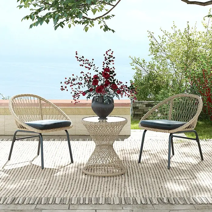 Outsunny Garten-Beistelltisch rund im Boho-Design - Stahl, PE-Rattan, Glas, Braun - Beige Korbmöbel-Set für die Terrasse: zwei Stühle mit schwarzen Kissen und ein Tisch, auf einem Teppich mit Garten- und Meerblick.