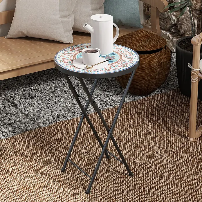 Outsunny Garten-Beistelltisch rund - Ø x H: 35,5 x 55 cm, Metall, Keramik, Mehrfarbig - Runder Klapptisch mit bunter Mosaikplatte und dunklen Metallbeinen, darauf eine Kaffeekanne und Tasse.
