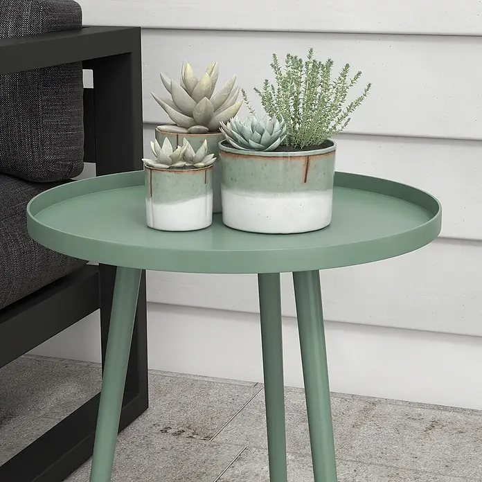 Outsunny Garten-Beistelltisch rund - Ø x H: 50 x 50 cm, Stahl, Grün - Grüner runder Beistelltisch mit drei Topfpflanzen, neben einem schwarzen Outdoor-Sessel platziert.