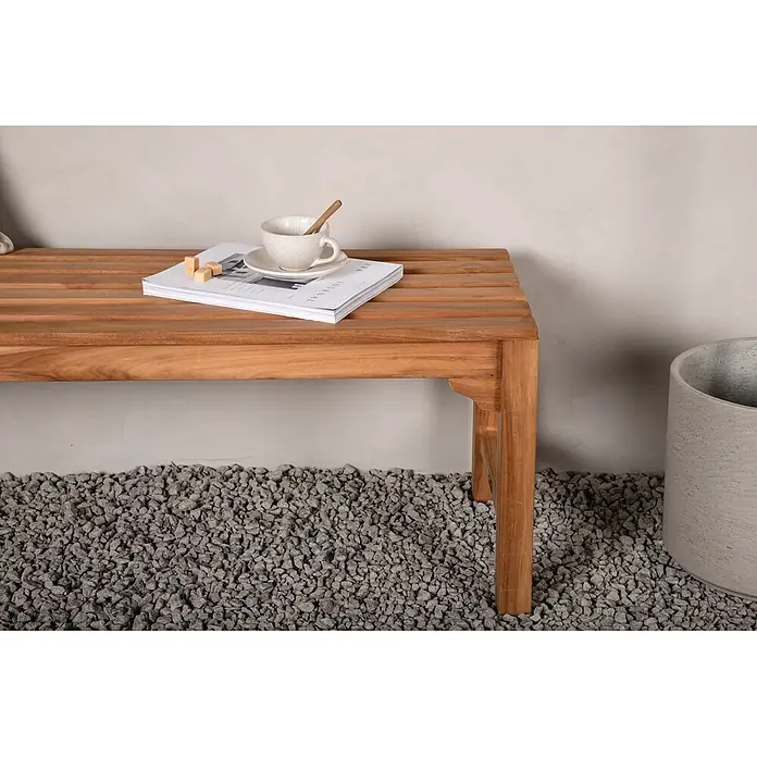 Ebuy24 Gartenbank Kenya - B x T x H: 150 x 150 x 45 cm, Teak, Holz - Hellbraune Holzbank mit Zeitschrift und Tasse, auf grauem Kiesboden.