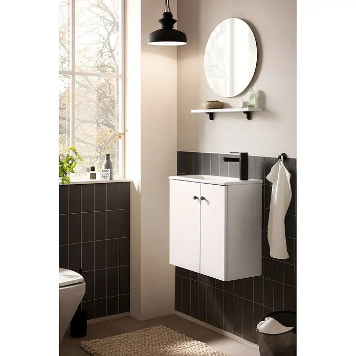 Schildmeyer Ebba Badmöbel-Set - Mattweiß - Weißer Badschrank mit schwarzem Wasserhahn und Griffen, mit weißem Waschbecken, unter einem Spiegel montiert.