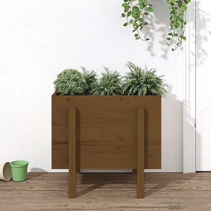 Furnicato Hochbeet - 50 x 62 x 57 cm, Holz, Honigbraune Kiefer - Brauner hölzerner Blumenkasten mit drei verschiedenen Grünpflanzen, auf einem Holzdeck stehend.
