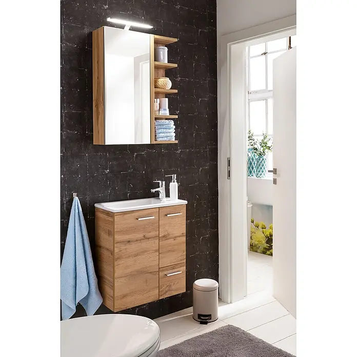 Schildmeyer LED-Spiegelschrank Matteo - B x H: 503 x 744 mm, Holz, Eiche Landhaus - Modernes Badmöbelset in Eichenoptik mit weißem Waschbecken, Spiegel und integrierter Beleuchtung, vor dunklen Fliesenwänden.