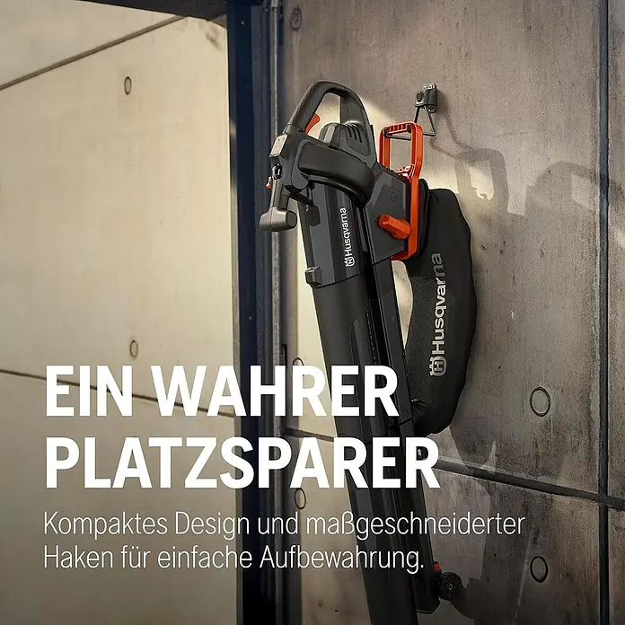 Husqvarna Akku-Laubsauger & -Laubbläser Aspire BVX-P4A - Ohne Akku, Blasgeschwindigkeit: 216 km/h - Schwarz-oranger Husqvarna Laubbläser/-sauger hängt an einem Wandhaken, demonstriert kompakte Aufbewahrung.