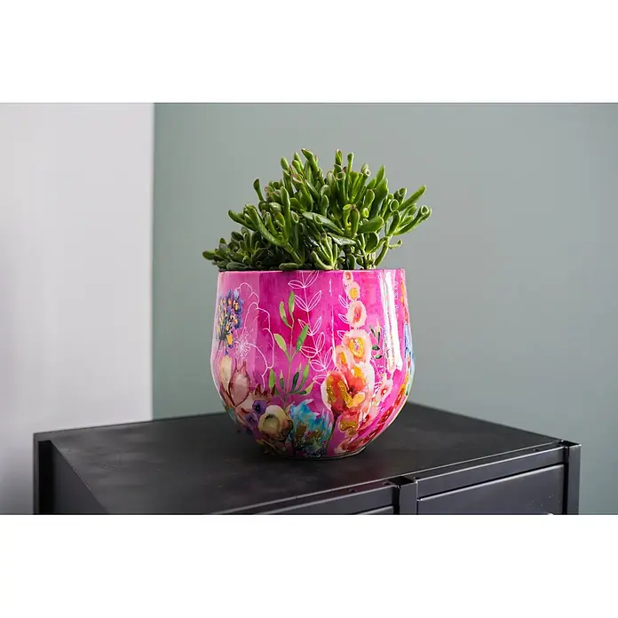 Ter Steege Übertopf rund Fiesta Fuchsie - Ø x H: 33 x 28 cm, Metall, Rosa/Pink - Lebendiger pinker Blumentopf mit bunten Blumenmustern, der eine grüne Sukkulente enthält, steht auf einer dunklen Oberfläche.