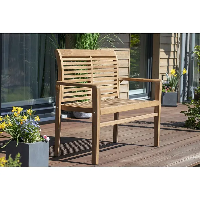 Bene Living Gartenbank Derby - B x T x H: 120 x 48 x 89 cm, Teakholz, Natur, Stapelbar - Gartenbank aus Teakholz mit Lattenrückenlehne und Sitzfläche, inklusive Armlehnen, auf einer Holzterrasse.