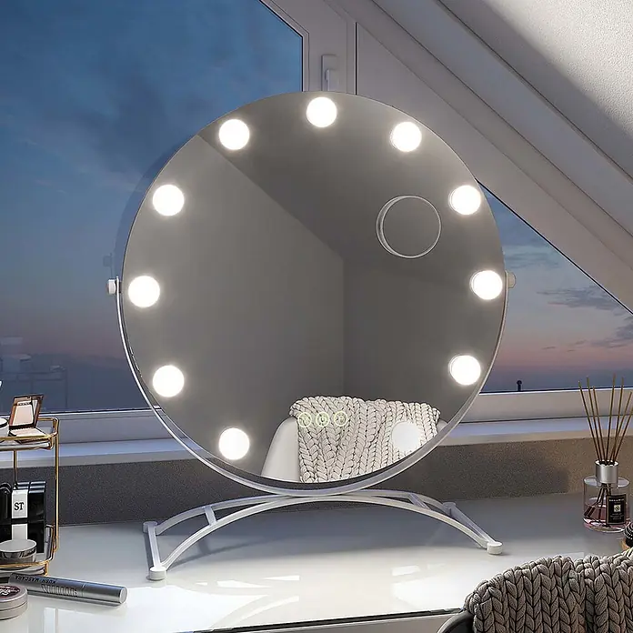 Emke Kosmetikspiegel CM11 - 50 x 58 cm, Rund, Weiß - Ein runder LED-Kosmetikspiegel mit Touch-Steuerung, auf einem weißen Schreibtisch vor einem Fenster, der einen Stuhl und eine Decke reflektiert.