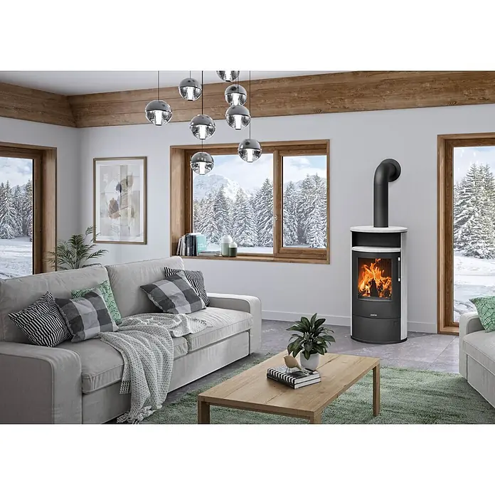Justus Kaminofen Island 7 2.0 - 7 kW, Raumheizvermögen: 144 m³, Farbe Verkleidung: Speckstein - Moderner schwarz-weißer Holzofen mit sichtbarem Feuer in einem gemütlichen Wohnzimmer.