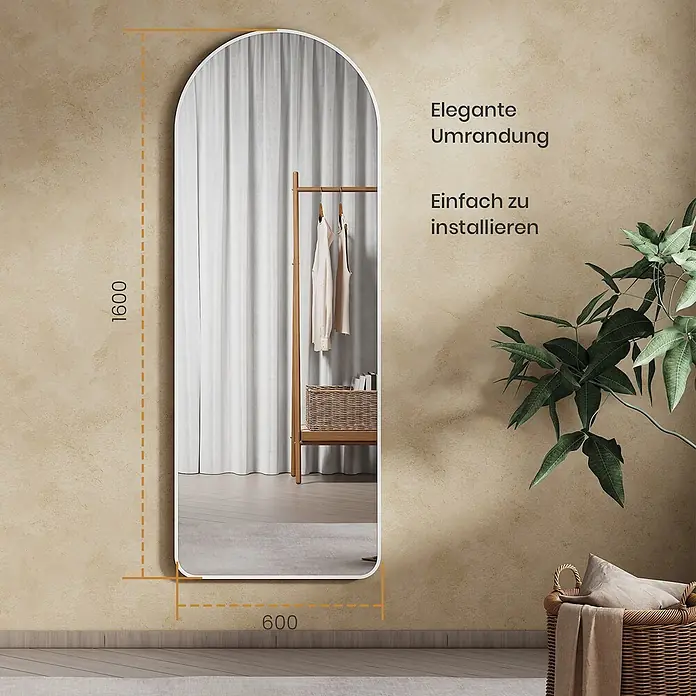Emke Standspiegel FM07 - Glas - Großer Bogen-Ganzkörperspiegel mit weißem Rahmen, 1600x600 mm, der einen Kleiderständer widerspiegelt.