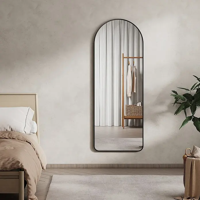 Emke Standspiegel - 60 x 160 cm, Glas - Bodenspiegel mit schwarzem Rahmen, gewölbt, in einem Schlafzimmer, reflektiert Kleiderständer und weiße Vorhänge.