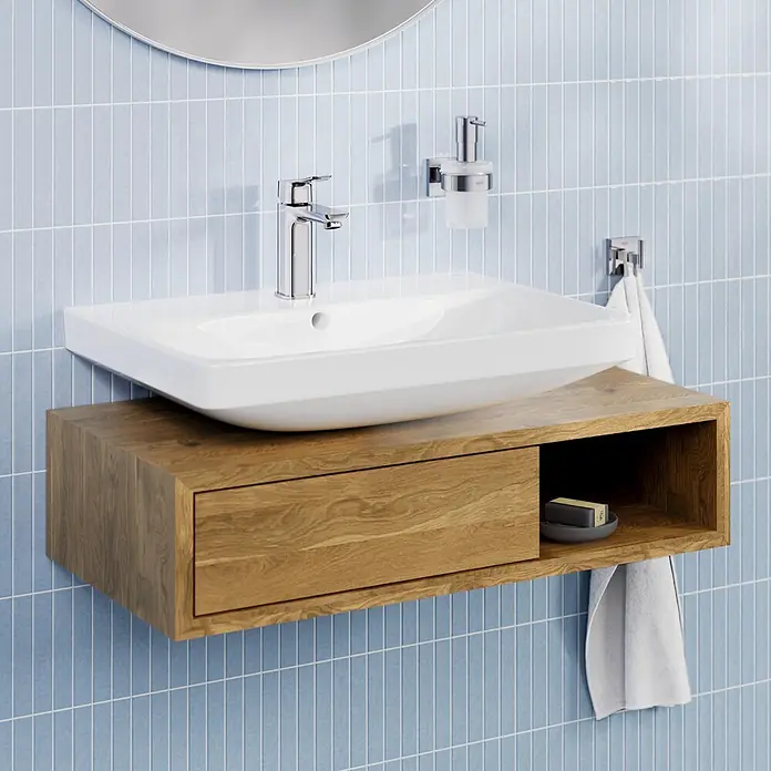 Grohe Dice Waschtischarmatur M-Size - Höhe: 172 mm, Chrom, Glänzend - Weißes Keramikwaschbecken auf wandmontiertem hellem Holzwaschtisch mit Schublade und offenem Regal, vor blauen Fliesen.