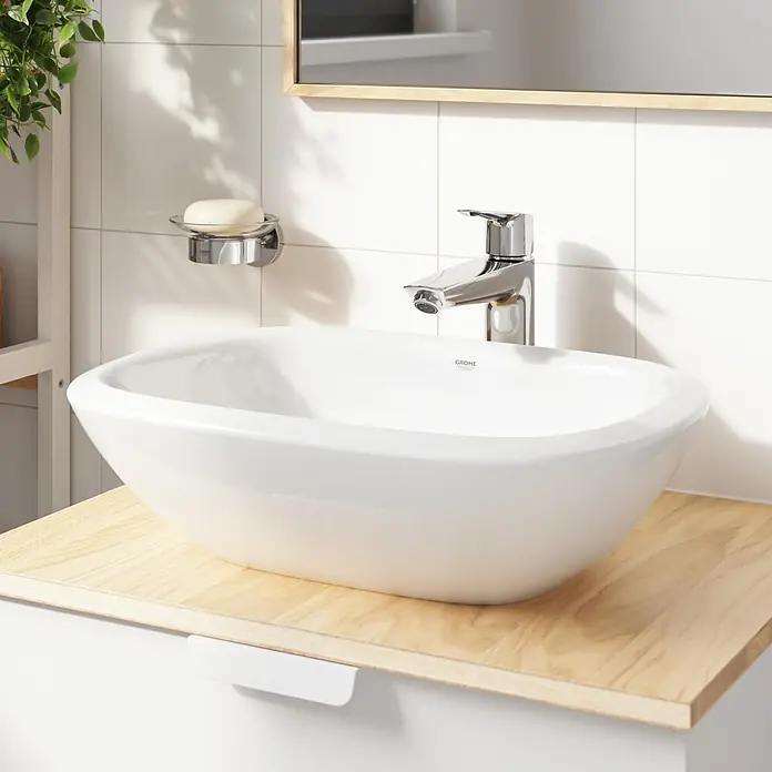 Grohe Start Waschtischarmatur XL-Size - Ausladung Armatur: 173 mm, Chrom, Glänzend - Weißes Keramik-Aufsatzwaschbecken mit Chromarmatur und Seifenschale auf einer hellen Holzwaschtischplatte im modernen Bad.