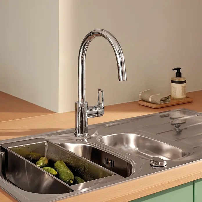 Grohe Start Loop Spültischarmatur - Chrom, Glänzend, Höhe: 357 mm - Ein glänzender Chrom-Küchenwasserhahn ist auf einer hellen Holztheke neben einer Edelstahlspüle mit Gurken in einem eingebauten Korb installiert.