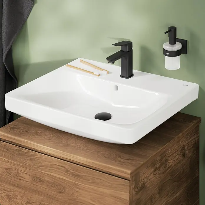 Grohe Dice Waschtischarmatur S-Size - Höhe: 152 mm, Schwarz, Matt - Weißes Keramikwaschbecken mit schwarzer Armatur auf Holzwaschtisch, mit Bambuszahnbürsten und Wandseifenspender.