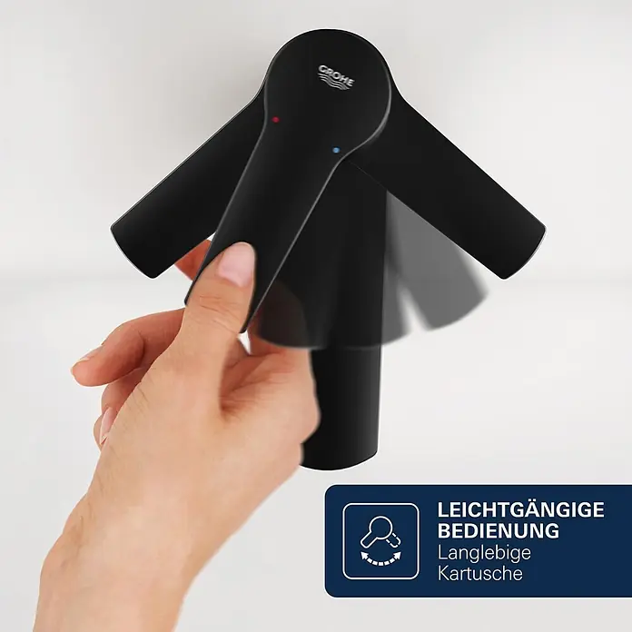 Grohe Start Loop Waschtischarmatur M-Size - Höhe: 164 mm, Schwarz, Matt - Eine Hand verstellt einen schwarzen Grohe Wasserhahnhebel mit roten und blauen Markierungen für leichtgängige Bedienung.