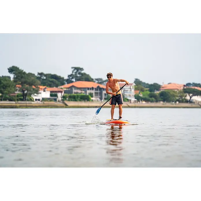 Aqua Marina SUP-Board-Set Atlas - L x B x H: 366 x 86 x 15 cm, Tragkraft: 180 kg, Orange - Ein Mann paddelt auf einem orange-roten Stand-Up Paddleboard mit einem blau-schwarzen Paddel auf dem Wasser.