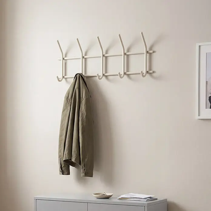 Spinder Design Garderobenleiste Ezra - L x B x H: 8,2 x 70 x 30 cm, Anzahl Haken: 10 Stk., Weiß - Weißes Metall-Garderobengestell mit mehreren Haken, an dem eine grüne Jacke hängt.