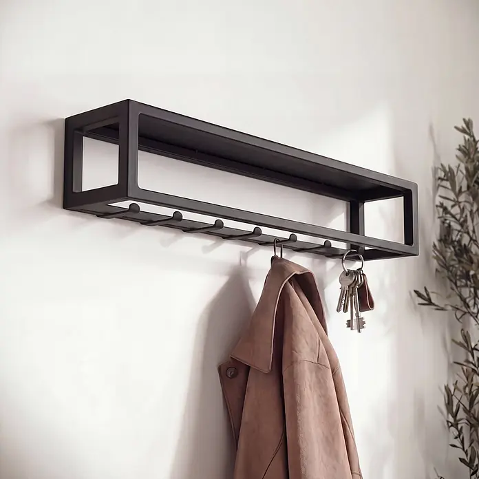 Spinder Design Garderobenleiste Axel 3 - L x B x H: 14 x 70 x 13 cm, Anzahl Haken: 7 Stk., Schwarz - Schwarzes Wandregal mit integrierten Haken, das eine beige Jacke und Schlüssel hält.