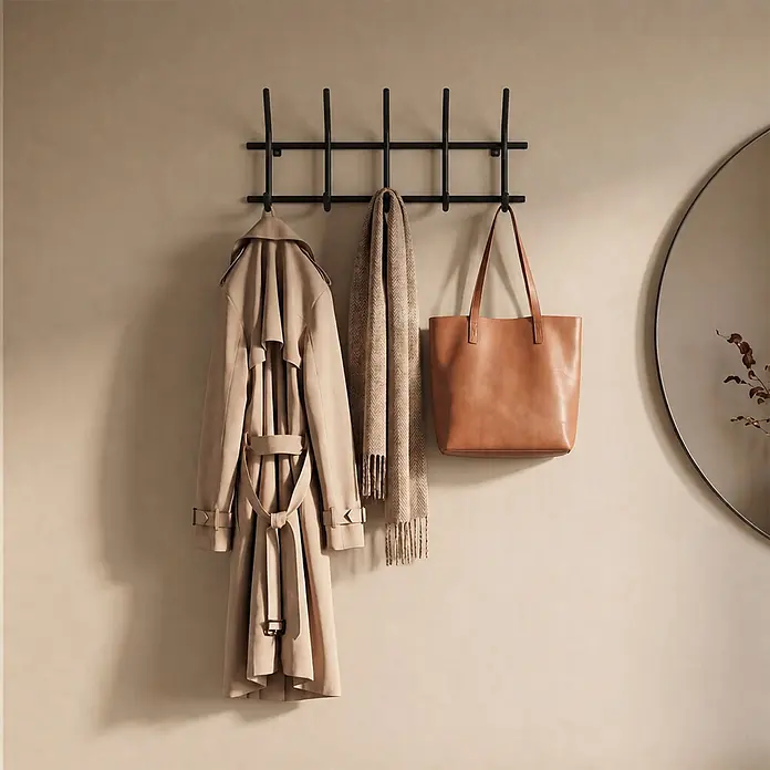 Spinder Design Garderobenleiste Ezra - L x B x H: 8,2 x 70 x 30 cm, Anzahl Haken: 10 Stk., Schwarz - Schwarze Metallgarderobe mit beigem Trenchcoat, beigem Schal und brauner Ledertasche.