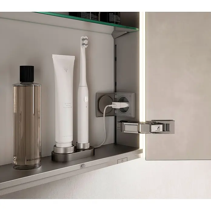 Keuco LED-Spiegelschrank Royal Vega - B x H: 100 x 71 cm, Aluminium, silber-eloxiert - Moderner Badschrank mit ladender elektrischer Zahnbürste, Zahnpasta und Mundspülung auf einem Regal, an interner Steckdose angeschlossen.