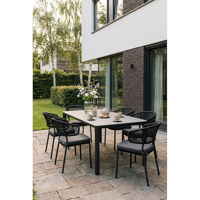 Barths Stapelstuhl Spitz - Aluminium, Seilgeflecht, Anthrazit, B x T x H: 59 x 66 x 82 cm - Outdoor-Essgarnitur auf Terrasse: grauer Tisch, schwarze Stühle mit grauen Kissen, gedeckt mit Tee und Blumen.