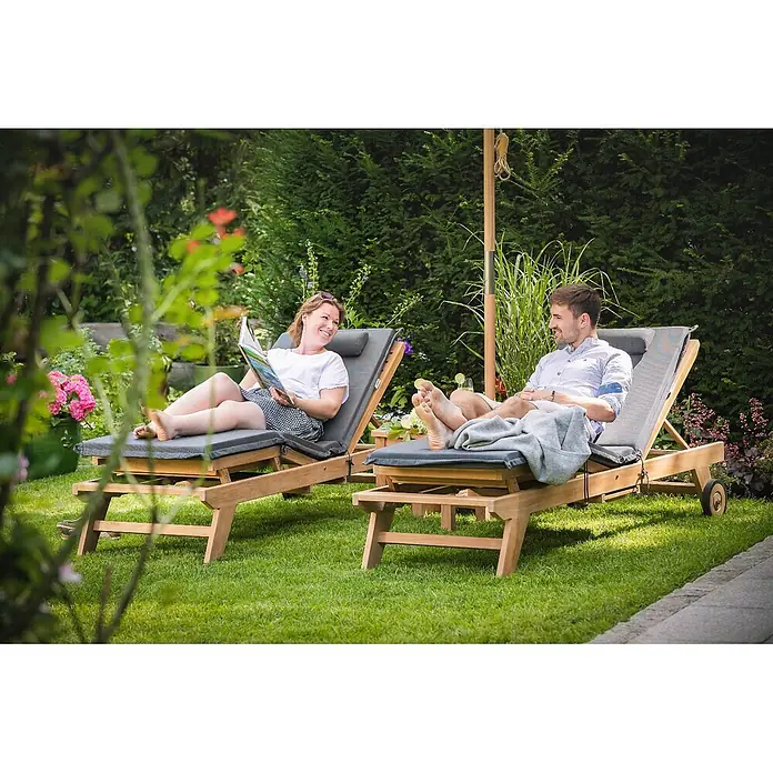 Kai Wiechmann Liegenauflage Polster mit Knick Anthrazit - Liege, Sonnenliege, Relaxliege, Polyacryl, Anthrazit - Zwei Holz-Sonnenliegen mit grauen Polstern, von einem Paar entspannt im Garten genutzt.