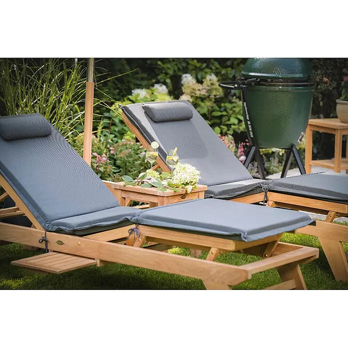 Kai Wiechmann Liegenauflage Polster mit Knick Anthrazit - Liege, Sonnenliege, Relaxliege, Polyacryl, Anthrazit - Zwei hölzerne Gartenliegen mit grauen Kissen, im Freien aufgestellt mit einem kleinen Tisch, Getränken und einem grünen Grill im Hintergrund.