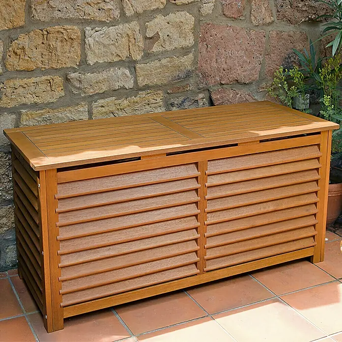 Sunfun Diana Garten-Aufbewahrungsbox - Braun, 127 x 51 x 62 cm, Holz - Holzkiste mit Lamellentüren auf einer Terrasse vor einer Steinmauer.