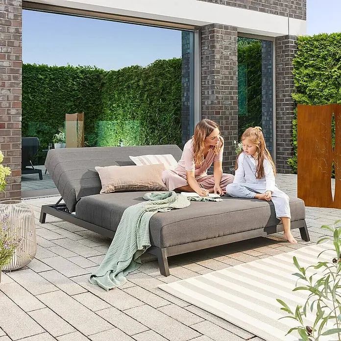 Home Deluxe Gartenliege VALENCIA - Grau, Sonstiges - Graues Outdoor-Loungesofa mit verstellbarer Rückenlehne, grauen Stoffpolstern, von zwei Personen auf Terrasse genutzt.