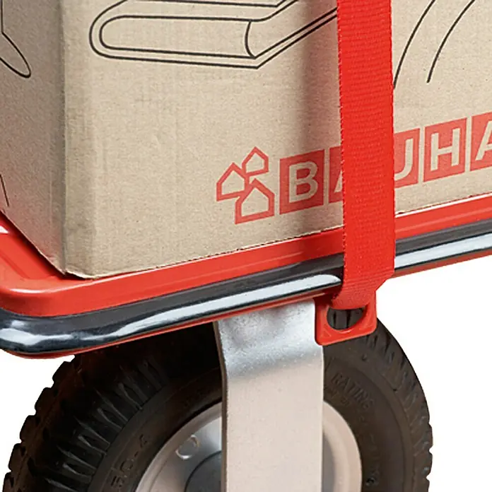 BAUHAUS Plattformwagen Cross Over - Stahl, 300 kg, Klappbar - Detailansicht eines roten Transportwagens mit Karton und rotem Gurt zur Ladungssicherung. Ideal für Umzüge und schwere Lasten.