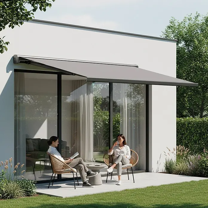 SmartSun Toldo con motor WiFi Dark Fiji II - Antracita, Ancho: 2,95 m, Caída: 2 m - Un toldo gris se extiende desde una casa moderna, dando sombra a un patio donde dos personas se relajan.