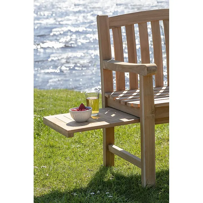 Bene Living Gartenbank Lancaster - Teakholz, Natur - Holzgartenbank mit integriertem Beistelltisch auf Gras am Wasser, mit Erdbeeren und Getränk.