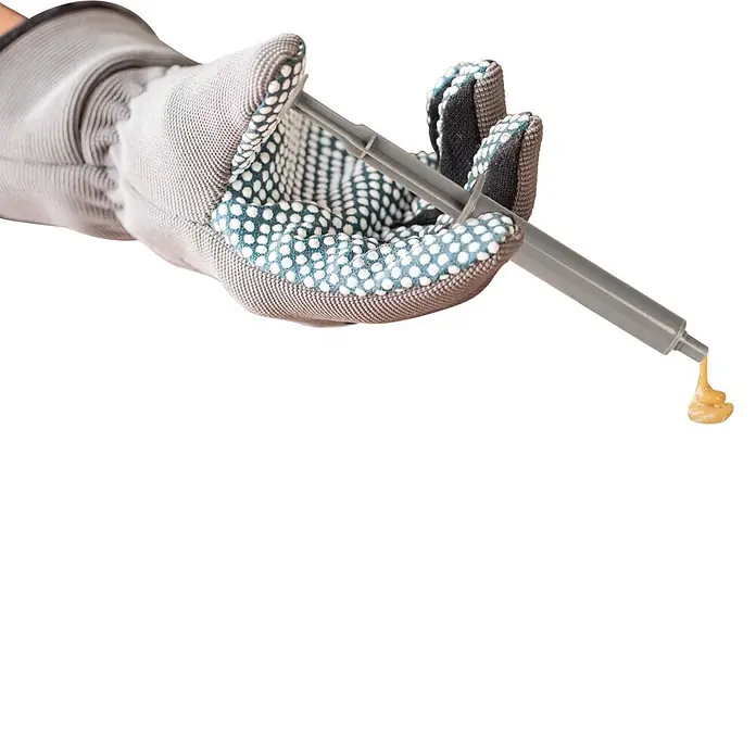 Windhager Ratten- & Mäuseköder Spritze - 2 Stk. - Behandschuhte Hand spendet gelbliches Gel aus grauem Applikator.
