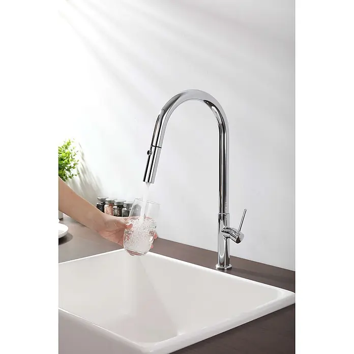Poalgi Spültischarmatur Space - Verchromt, Glänzend - Verchromte ausziehbare Küchenarmatur füllt ein Wasserglas, das von einer Hand über einem weißen Spülbecken gehalten wird.
