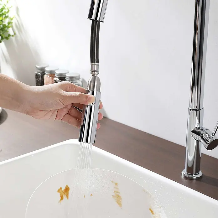 Poalgi Spültischarmatur Space - Verchromt, Glänzend - Hand hält verchromte Ausziehbrause, die Wasser auf schmutzigen Teller im Spülbecken sprüht.