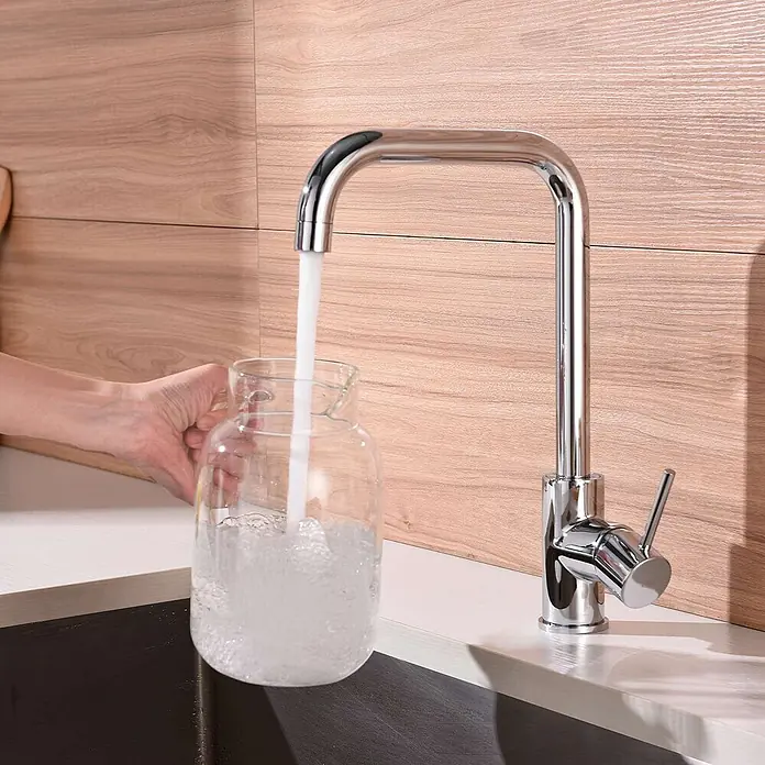 Poalgi Spültischarmatur Comfort - Verchromt, Glänzend - Verchromte Küchenarmatur mit elegantem, quadratischem Auslauf, die einen Glaskrug mit Wasser füllt.