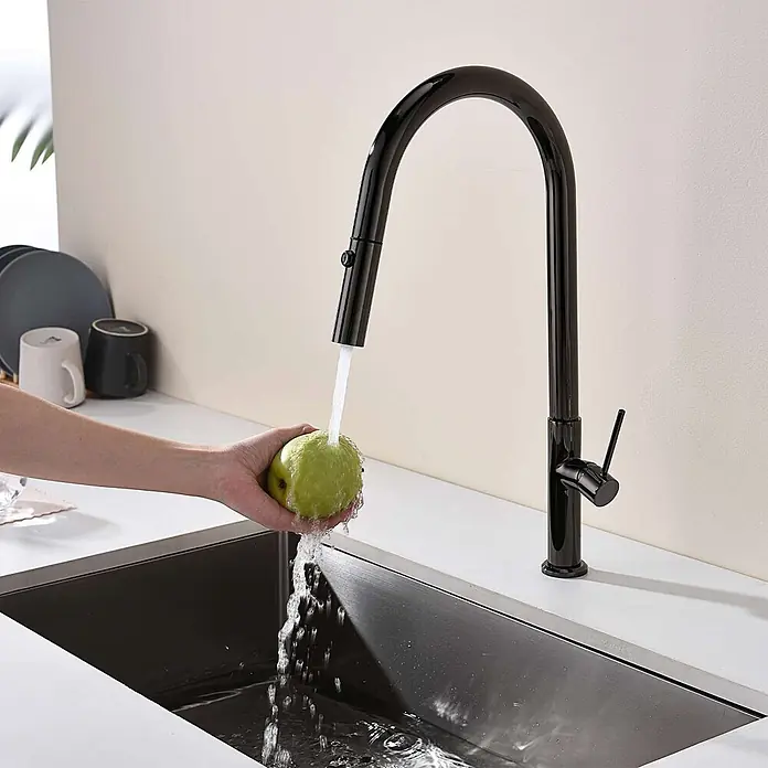 Poalgi Spültischarmatur Space - Kristallschwarz, Glänzend - Schwarze Hochbogen-Küchenarmatur, die Wasser über eine grüne Frucht in ein Spülbecken abgibt.