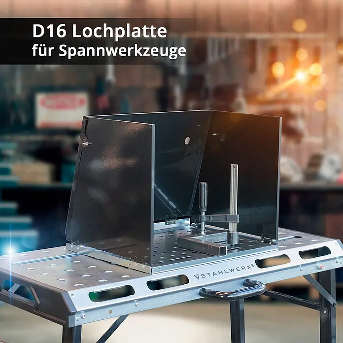 STAHLWERK Schweißtisch Schweißtisch-Aufsatz SA-500 ST -  - Schwarzer Metall-Spritzschutz mit D16-Löchern auf einem Schweißtisch, der ein Werkstück mit einer Klemme hält.