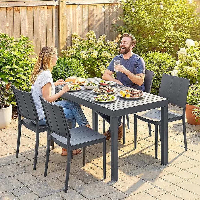 Outsunny Gartentisch-Set - Gesamtumfang: 5 -tlg., L x B x H: 141,5 x 70,5 x 74,5 cm, Metall, Kunststoff, Stapelbar - Grauer Outdoor-Esstisch und Stühle, von zwei Personen für eine Mahlzeit auf einer sonnigen Terrasse genutzt.